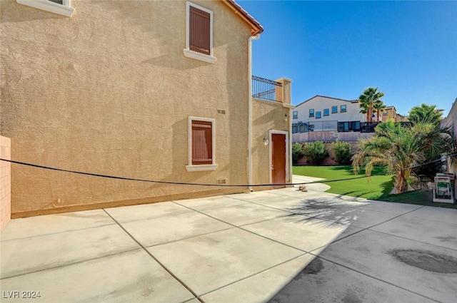 view of property exterior with a balcony and a lawn