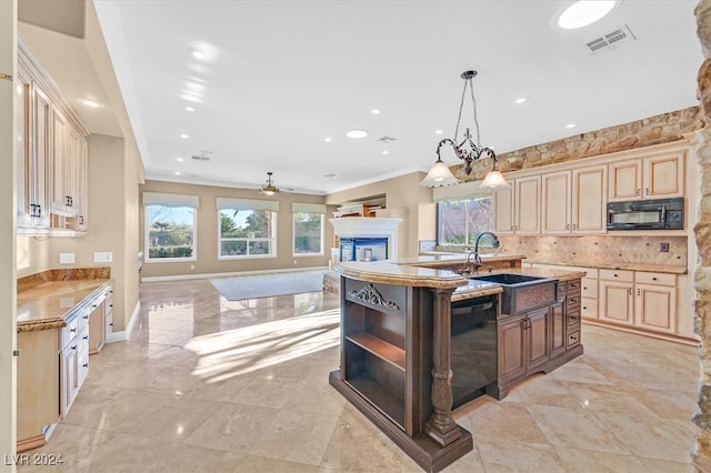 kitchen featuring decorative backsplash, ceiling fan with notable chandelier, a kitchen island with sink, black appliances, and pendant lighting