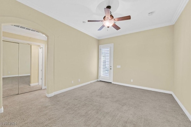 carpeted spare room with ceiling fan and ornamental molding