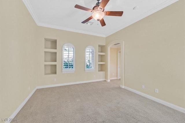 empty room with ceiling fan, light colored carpet, built in features, and crown molding