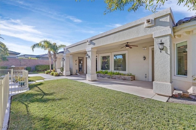 rear view of property with a lawn and ceiling fan