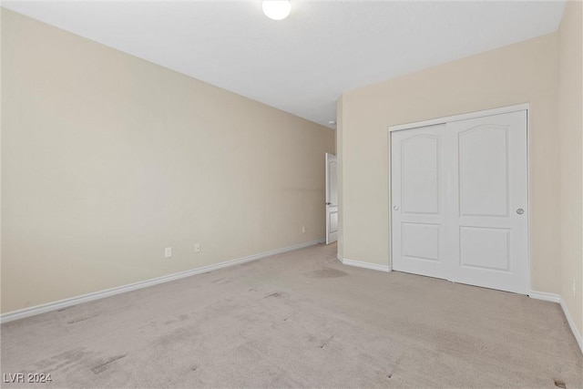 unfurnished bedroom with light colored carpet and a closet