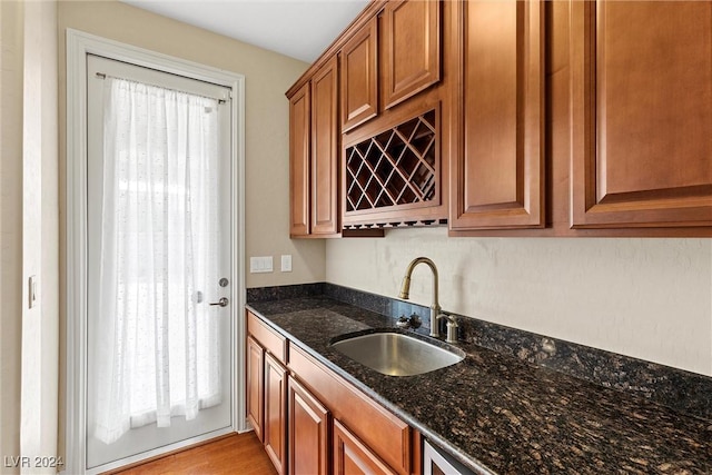 kitchen featuring dark stone countertops, sink, and light wood-type flooring