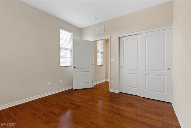 unfurnished bedroom featuring dark hardwood / wood-style floors and a closet