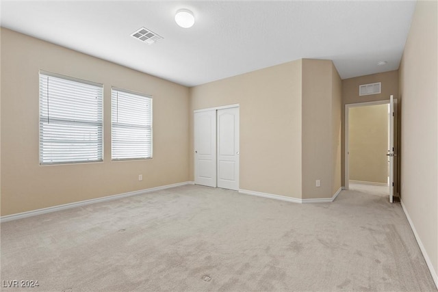 unfurnished bedroom featuring light colored carpet and a closet