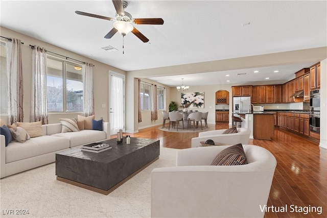 living room featuring ceiling fan with notable chandelier and light hardwood / wood-style flooring