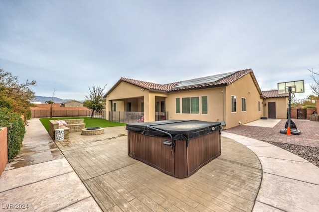 back of property featuring a patio, a hot tub, and a fire pit