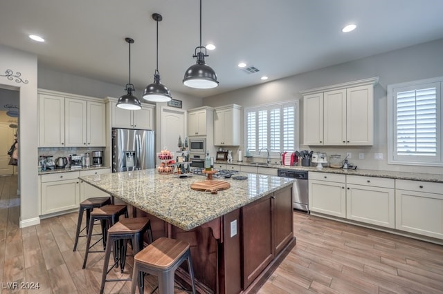 kitchen with light stone countertops, stainless steel appliances, sink, white cabinets, and a kitchen island