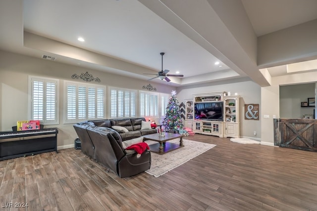 living room with a tray ceiling, ceiling fan, and hardwood / wood-style flooring