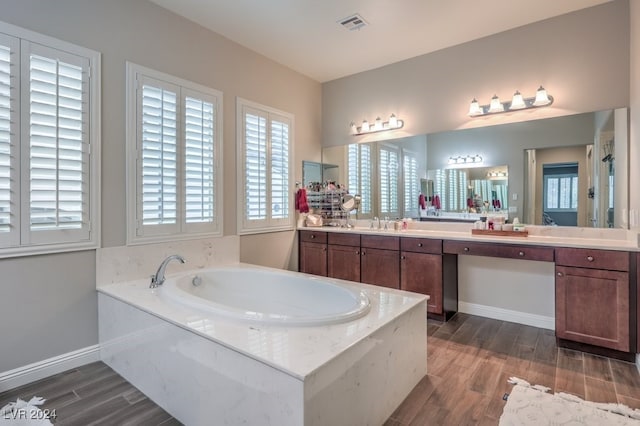 bathroom with hardwood / wood-style flooring, vanity, and a tub to relax in