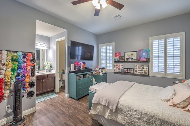 bedroom with ceiling fan, sink, ensuite bathroom, wood-type flooring, and multiple windows