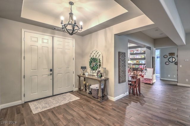 foyer entrance featuring a chandelier, a tray ceiling, and dark hardwood / wood-style floors