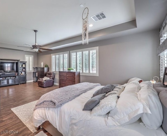 bedroom with a raised ceiling, ceiling fan, and dark hardwood / wood-style floors