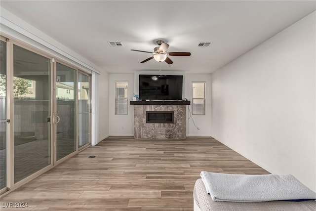 unfurnished living room with ceiling fan, a high end fireplace, and light wood-type flooring