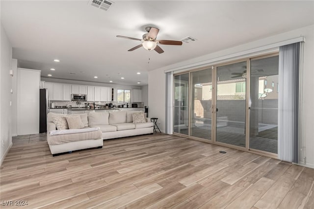 living room with ceiling fan and light hardwood / wood-style flooring