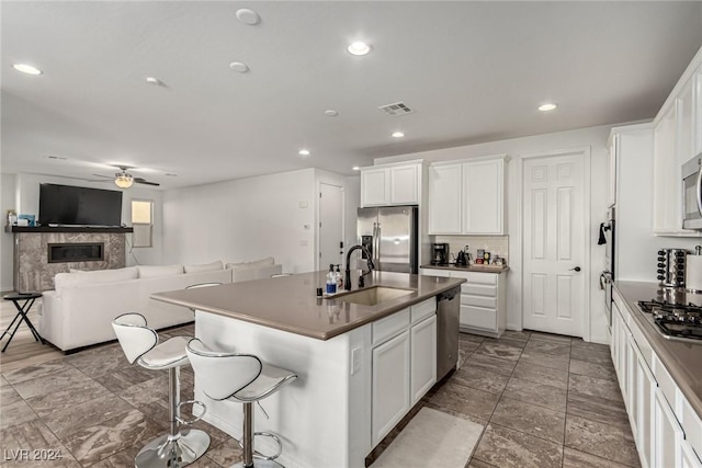 kitchen with stainless steel appliances, a kitchen island with sink, sink, and white cabinets