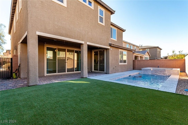 back of property with a patio, a fenced in pool, and a lawn