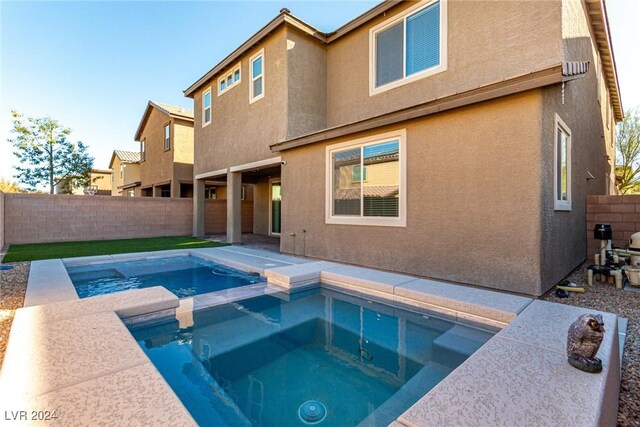 rear view of property featuring an in ground hot tub