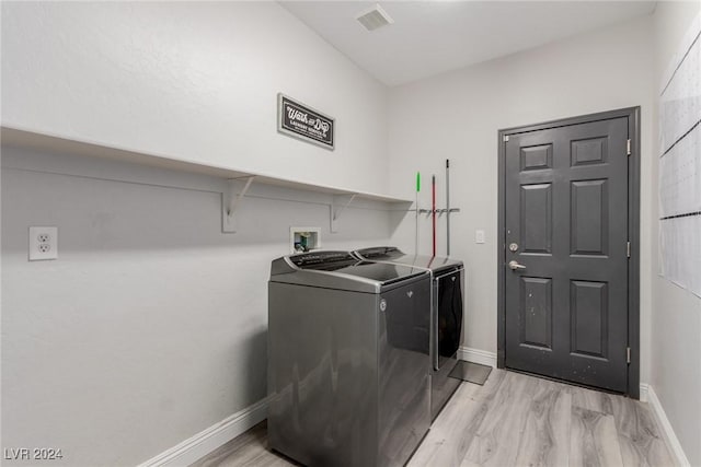 clothes washing area featuring separate washer and dryer and light hardwood / wood-style flooring