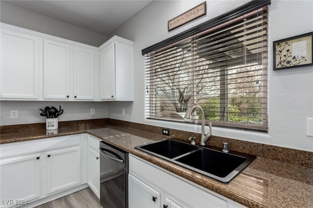 kitchen featuring dark stone counters, white cabinetry, stainless steel dishwasher, and sink