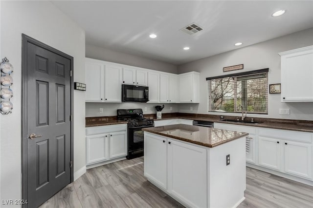 kitchen featuring sink, black appliances, white cabinets, a center island, and light hardwood / wood-style floors