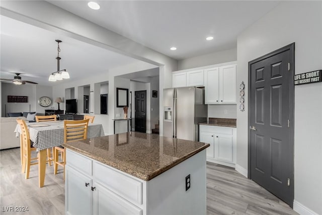 kitchen with dark stone counters, white cabinetry, ceiling fan, a kitchen island, and stainless steel fridge with ice dispenser