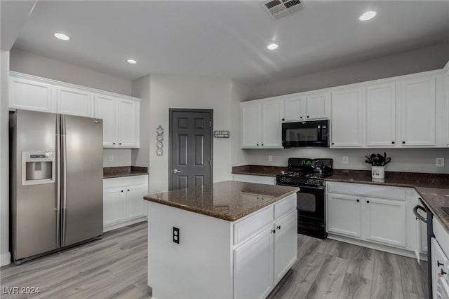 kitchen with a kitchen island, black appliances, dark stone countertops, light hardwood / wood-style floors, and white cabinetry