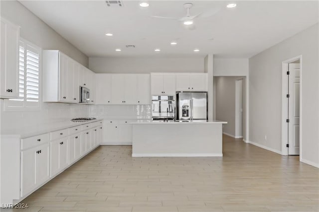 kitchen featuring appliances with stainless steel finishes, tasteful backsplash, ceiling fan, a center island, and white cabinetry