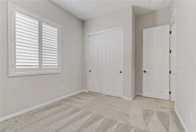 unfurnished bedroom with light carpet and a closet