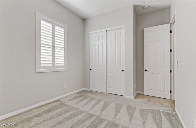 unfurnished bedroom with light carpet and a closet