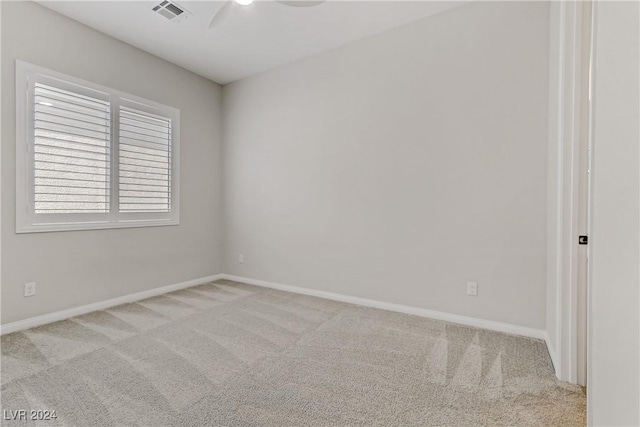 empty room featuring ceiling fan and light carpet