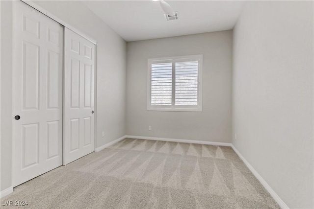 unfurnished bedroom featuring light carpet, a closet, and ceiling fan