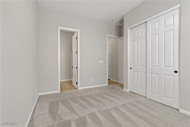 unfurnished bedroom featuring ensuite bathroom, a closet, and light colored carpet