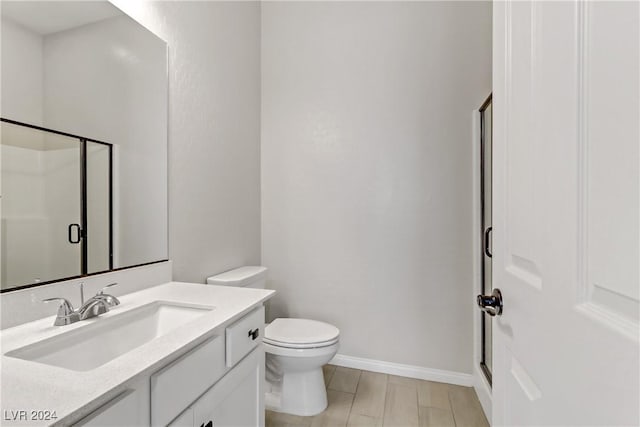 bathroom with a shower with door, vanity, and toilet