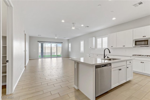 kitchen with a wealth of natural light, ceiling fan, stainless steel appliances, a kitchen island with sink, and white cabinets