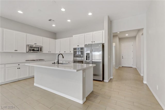 kitchen with a kitchen island with sink, white cabinetry, sink, and appliances with stainless steel finishes