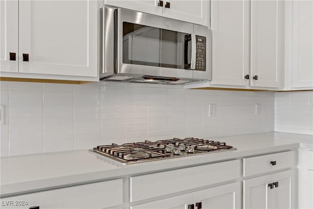 kitchen featuring decorative backsplash, white cabinetry, and appliances with stainless steel finishes