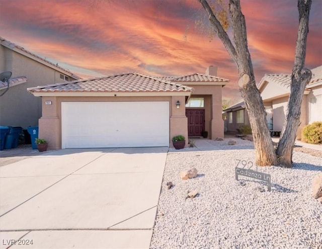 view of front of home with concrete driveway, a tile roof, stucco siding, a chimney, and an attached garage