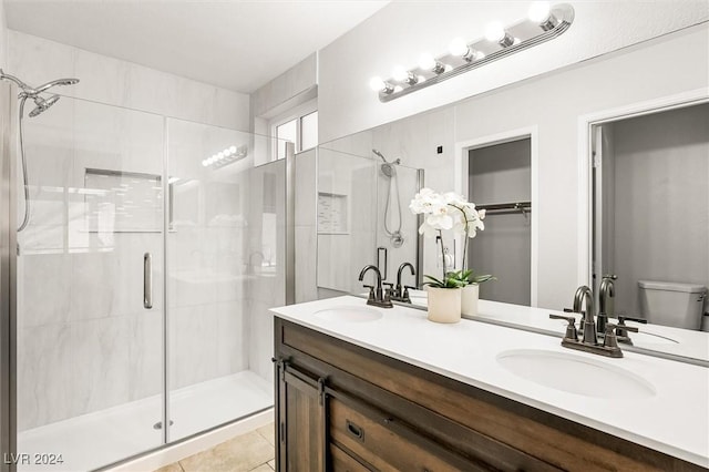 full bathroom with a sink, toilet, a stall shower, and double vanity