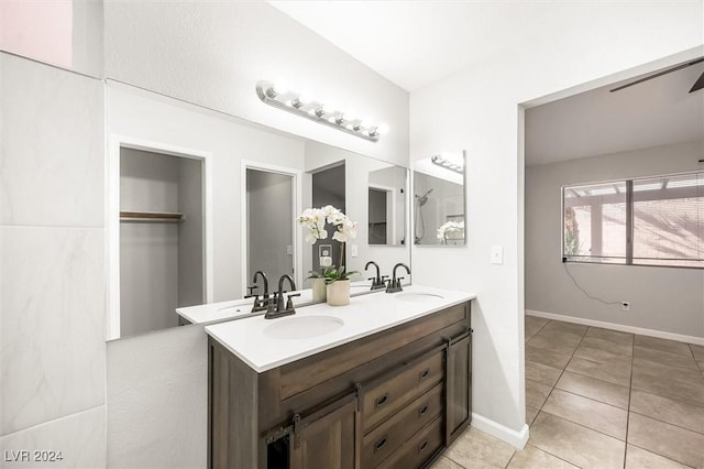 bathroom with double vanity, tile patterned floors, baseboards, and a sink