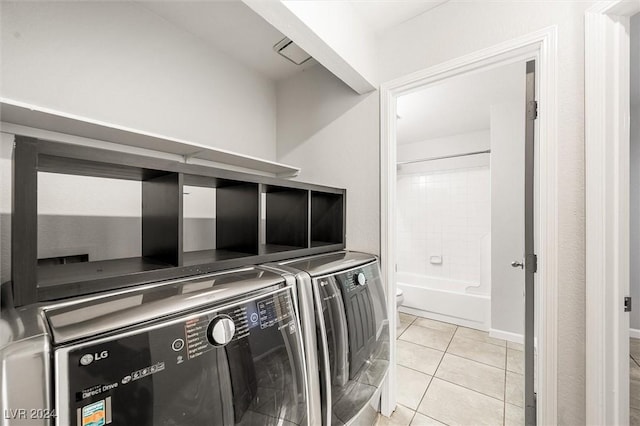 clothes washing area featuring laundry area, light tile patterned floors, and washer and clothes dryer