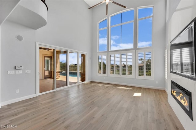 unfurnished living room with light wood-type flooring and a high ceiling