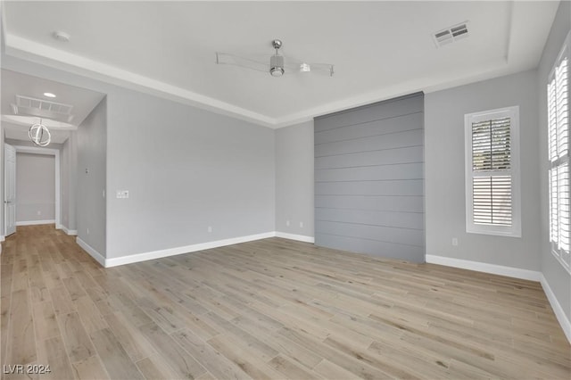 spare room featuring ceiling fan, a raised ceiling, and light hardwood / wood-style flooring