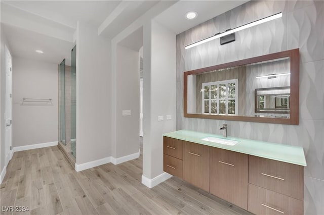 bathroom with hardwood / wood-style floors, vanity, and an enclosed shower