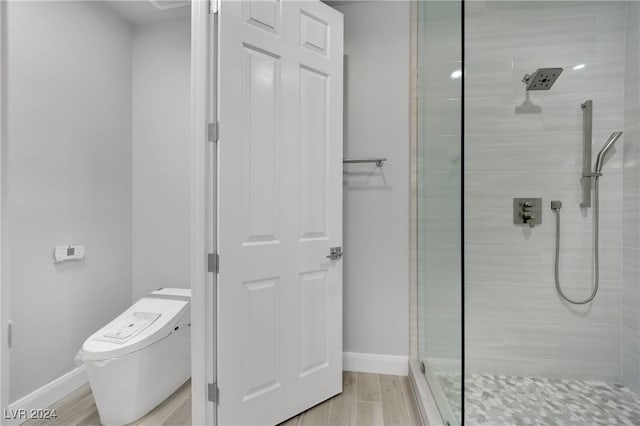 bathroom with a tile shower, hardwood / wood-style floors, and toilet