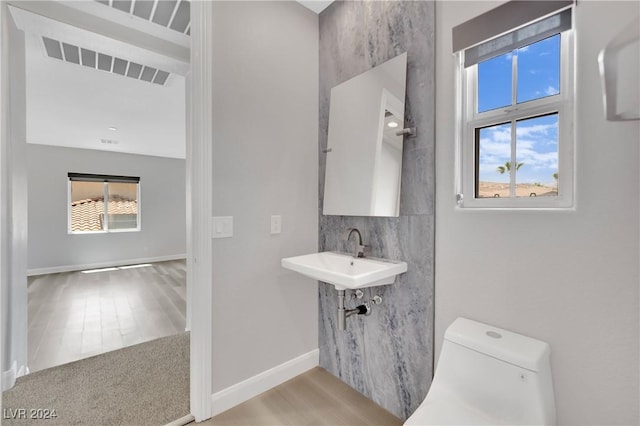 bathroom featuring backsplash, toilet, and sink