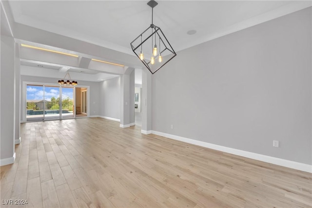 empty room with light hardwood / wood-style flooring and an inviting chandelier