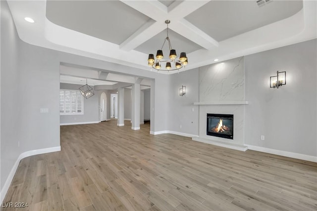 unfurnished living room with coffered ceiling, a fireplace, beamed ceiling, and light hardwood / wood-style flooring