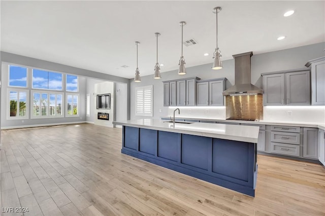 kitchen with pendant lighting, gray cabinetry, wall chimney range hood, sink, and black electric cooktop