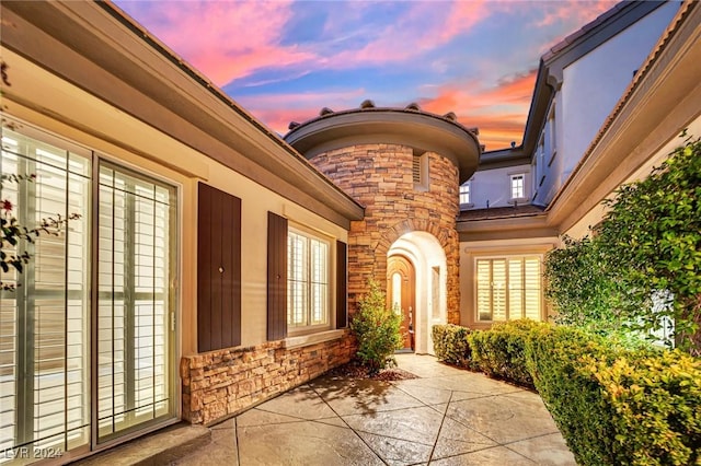 exterior entry at dusk featuring a patio area